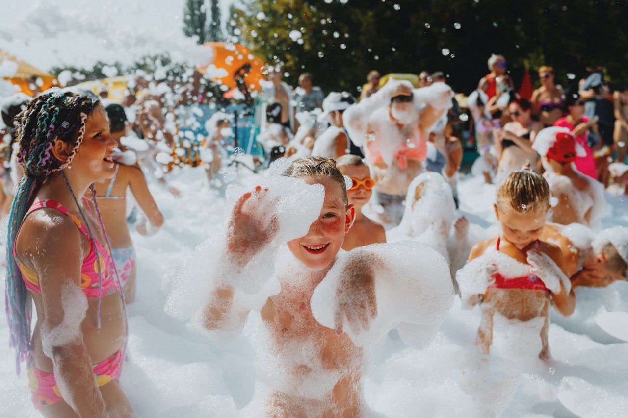 Children enjoying a playful foam party outdoors, capturing summer joy and excitement.