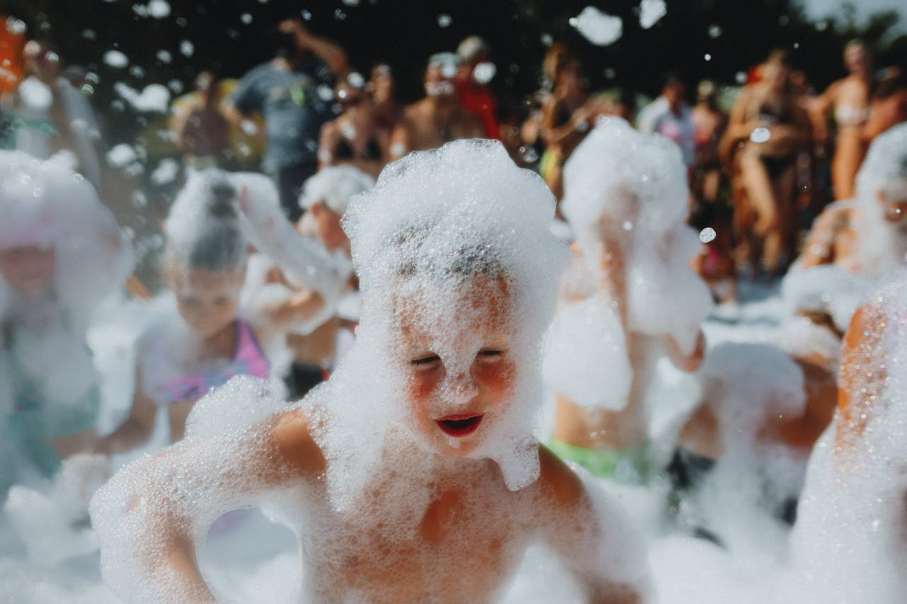 Kids having fun in a lively foam party, enjoying bubbles and sunshine outdoors.